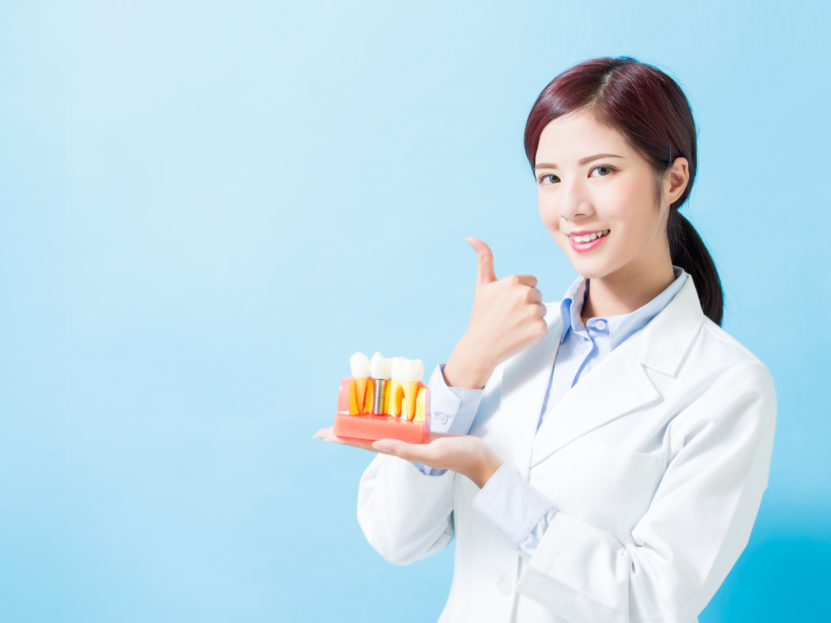 A dentist is showing a patient a model of cosmetic dental implants